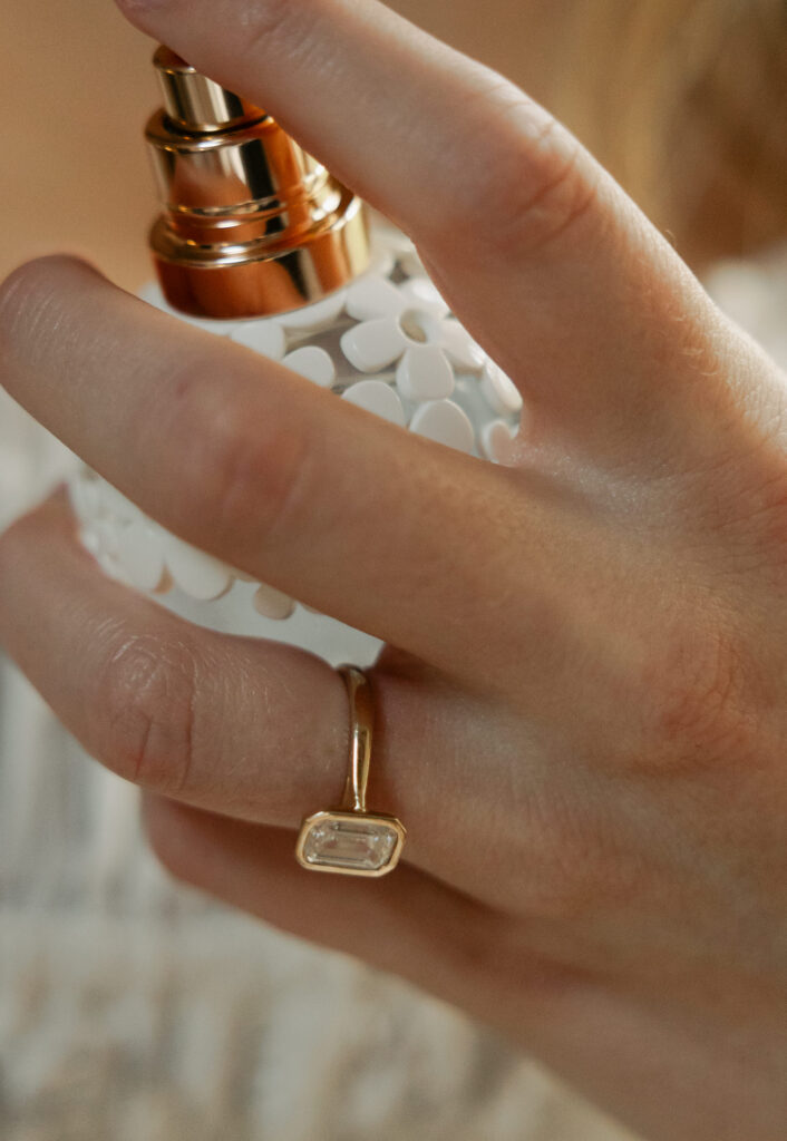 bride spraying perfume with wedding ring hand