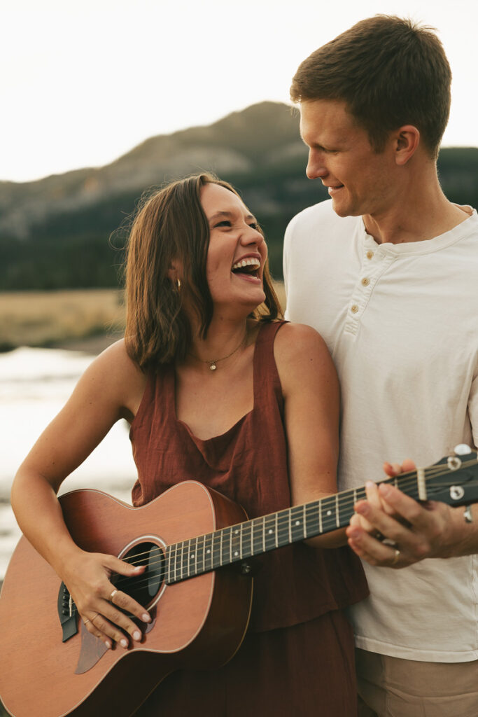 bride and groom laughing as they play guitar during engagement shoot