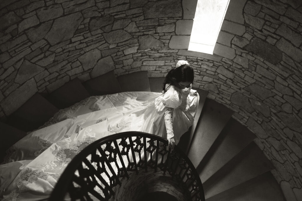 bride walking down spiral stairs with train following behind her