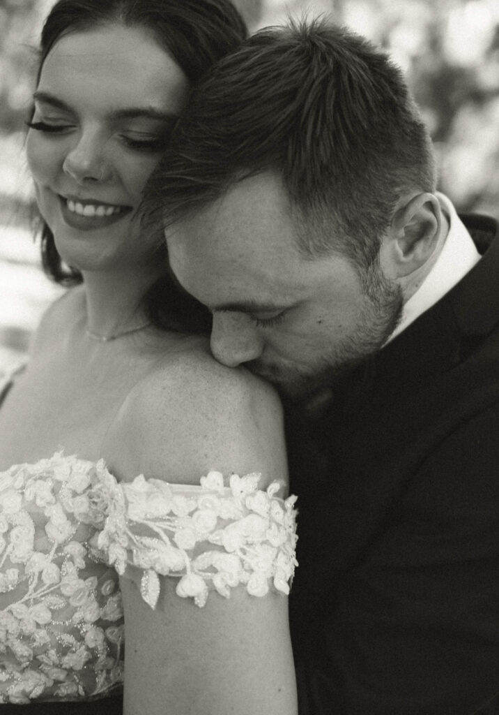 close up of groom kissing brides shoulder