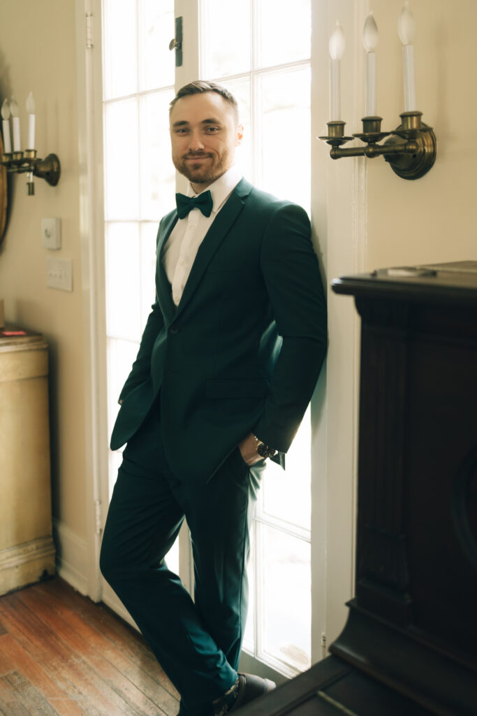 groom leaning on door and posing