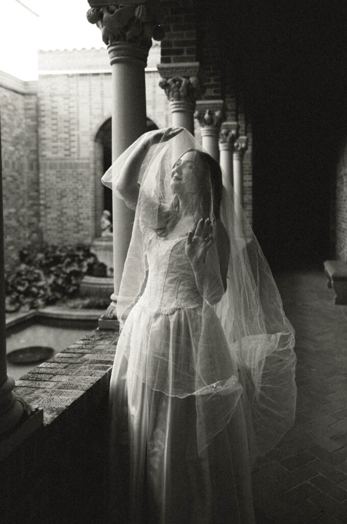 bride's veil in over her head and she is holding it up with her hands