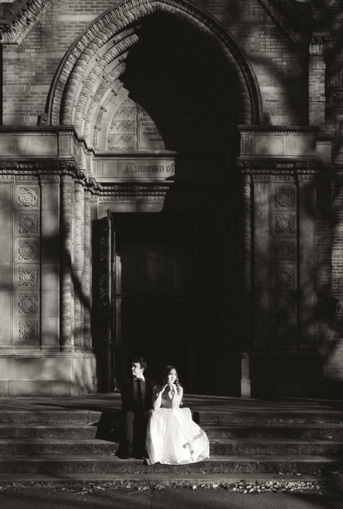 bride and groom sitting on steps outside of museum