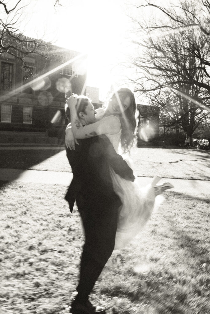 playful wedding portrait of groom swinging bride