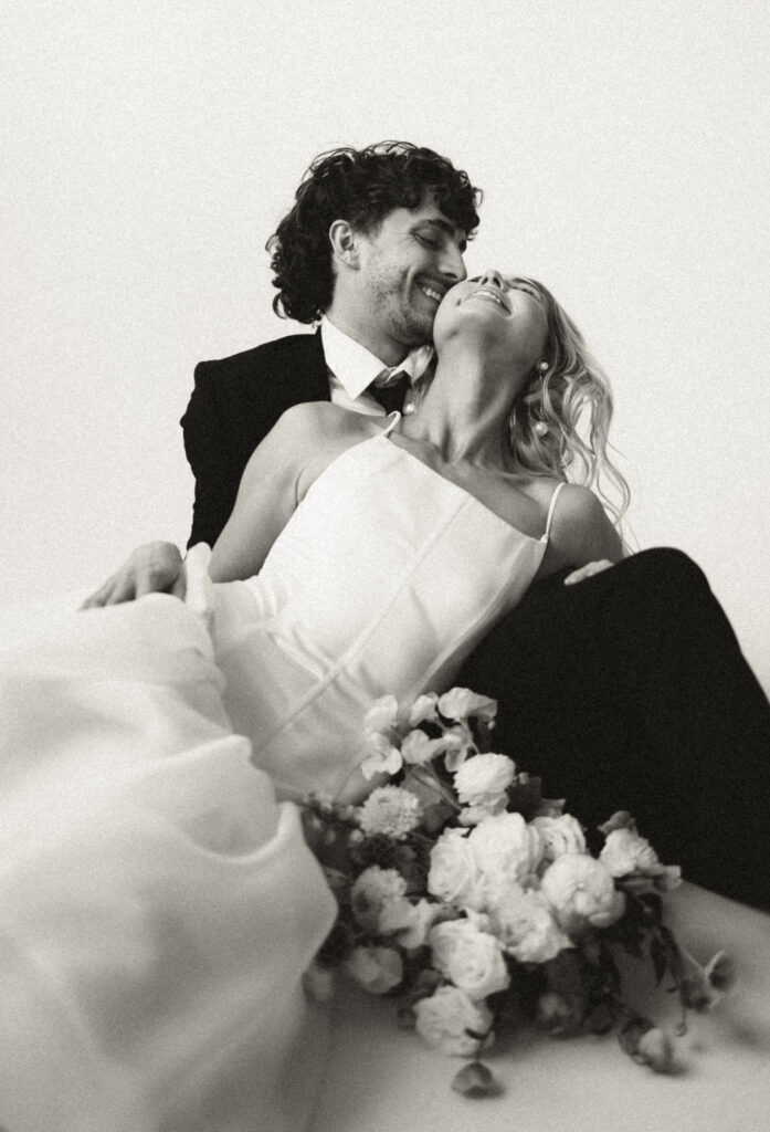 bride and groom laughing while laying down