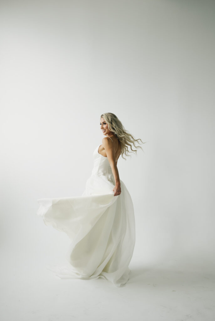 bride facing away and tossing dress