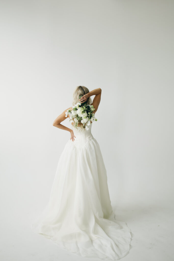 bride turned away and holding her bouquet behind her head