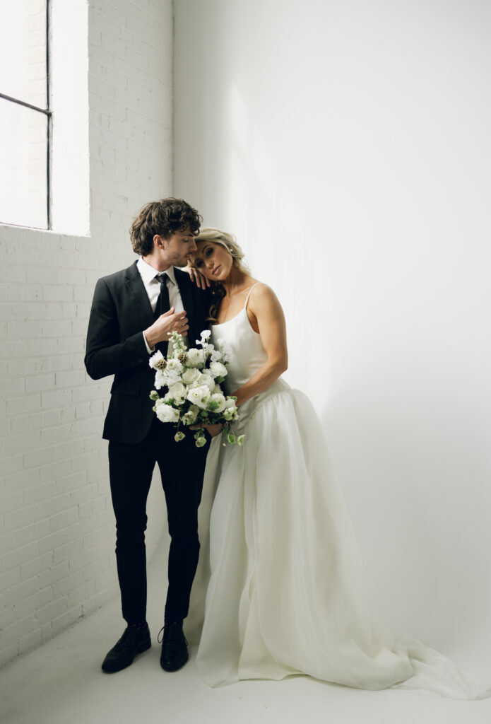 bride leading on groom's shoulder and looking at camera