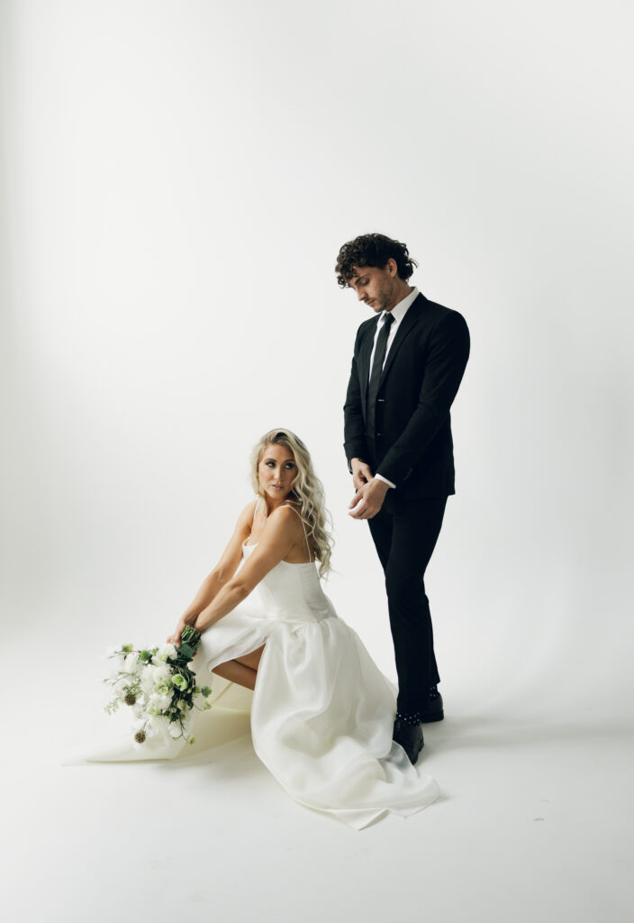 bride squatting and groom standing beside her