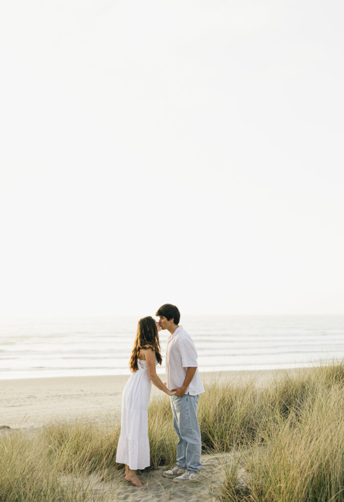 couple kisses during engagement photos at beach