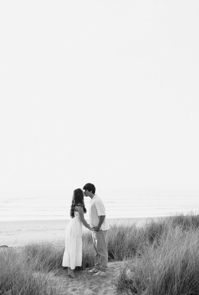 black and white photo of couple kissing at beach during engagement photos