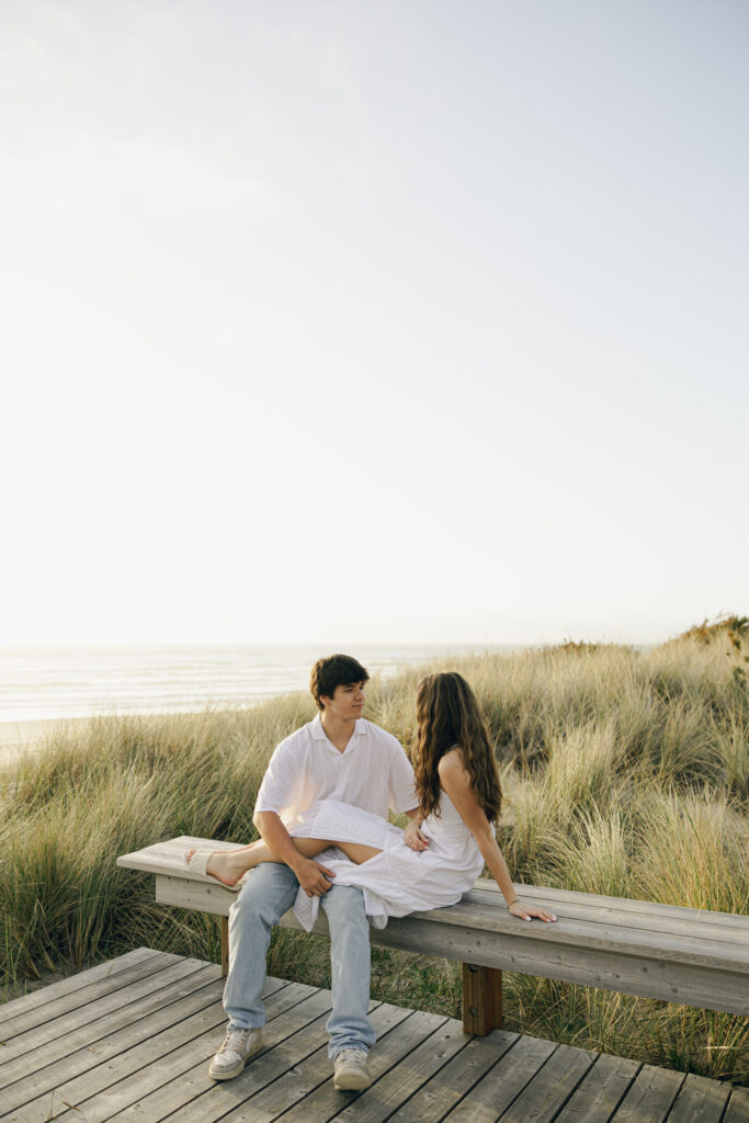 couple sitting on beach platform and talking during engagement photos
