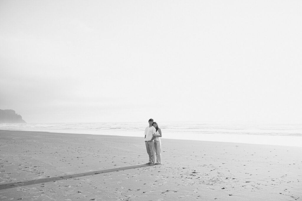grand photo of an engaged couple on wide open beach