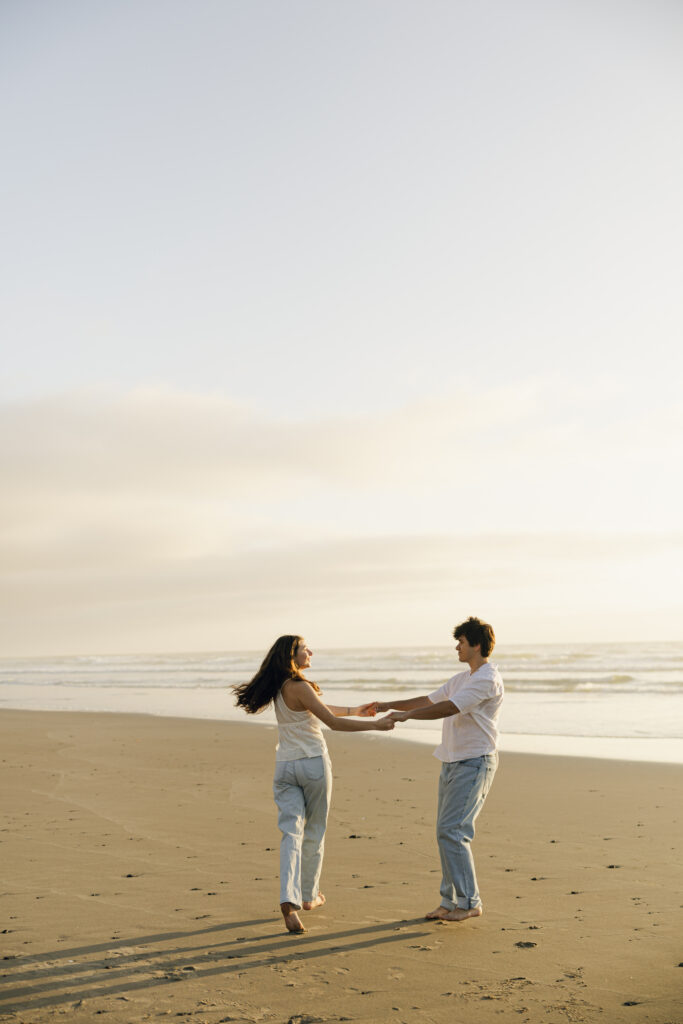 couple swinging on beach during engagement photos