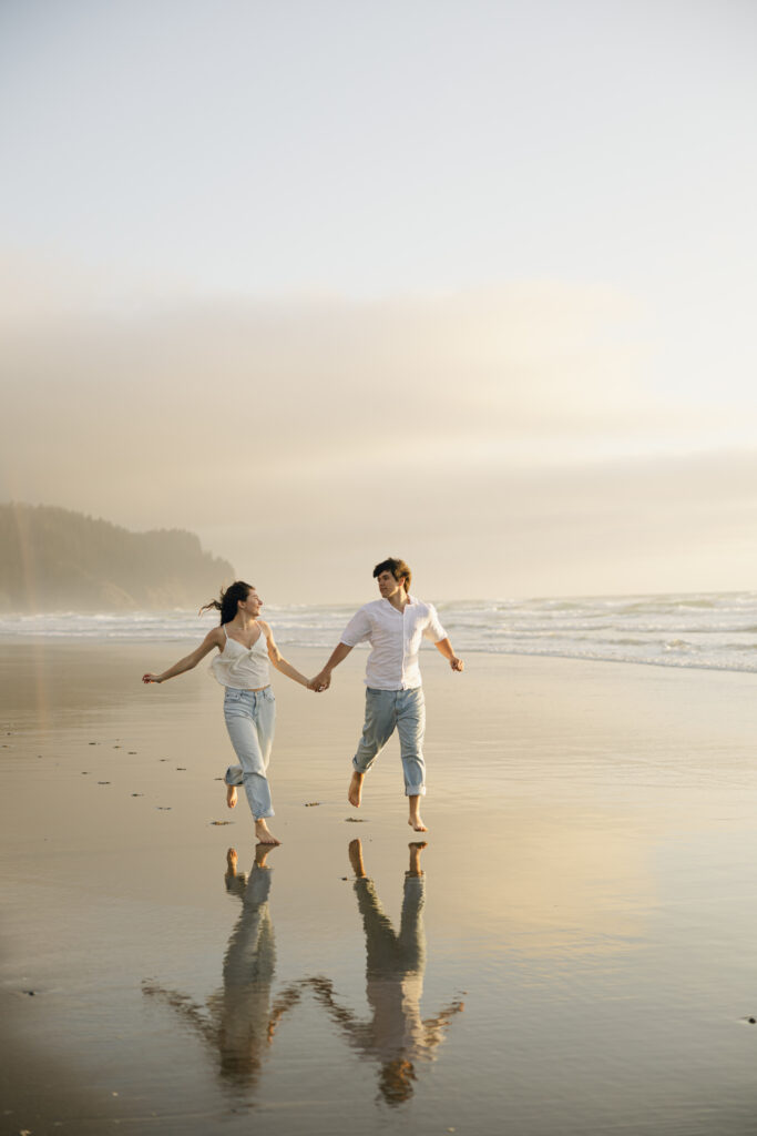 engaged couple running at beach in oregon