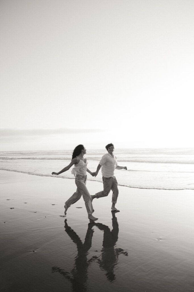black and white edit of couple running at beach