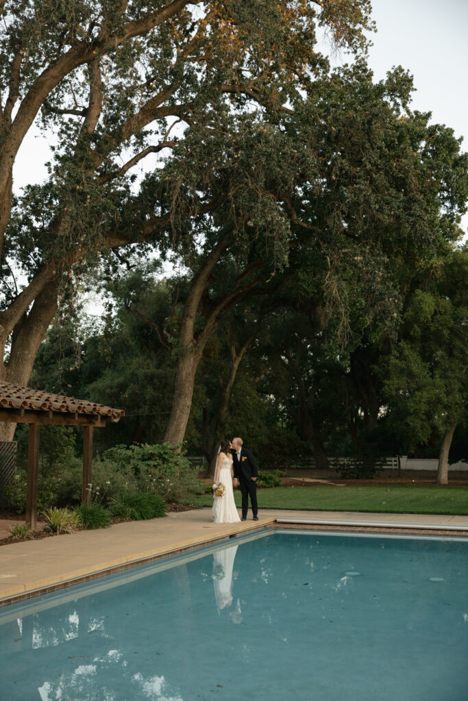 bride and groom standing at corner of pool