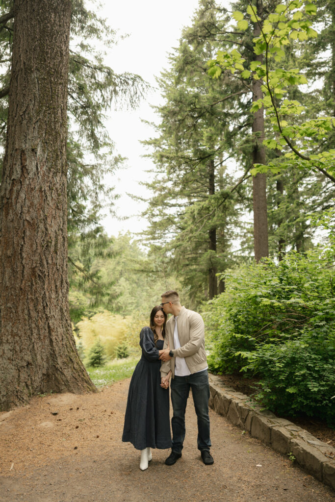 couple holding hands leaning into each other as man kisses womans temple