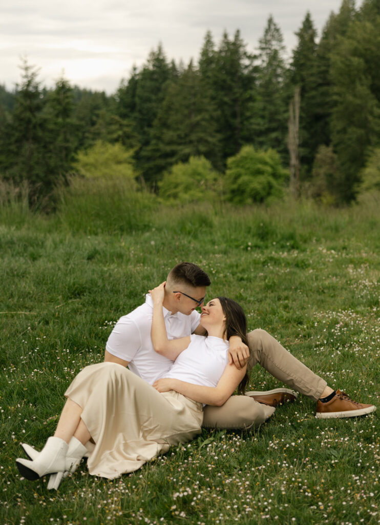 man sits and woman lays on his lap and kisses