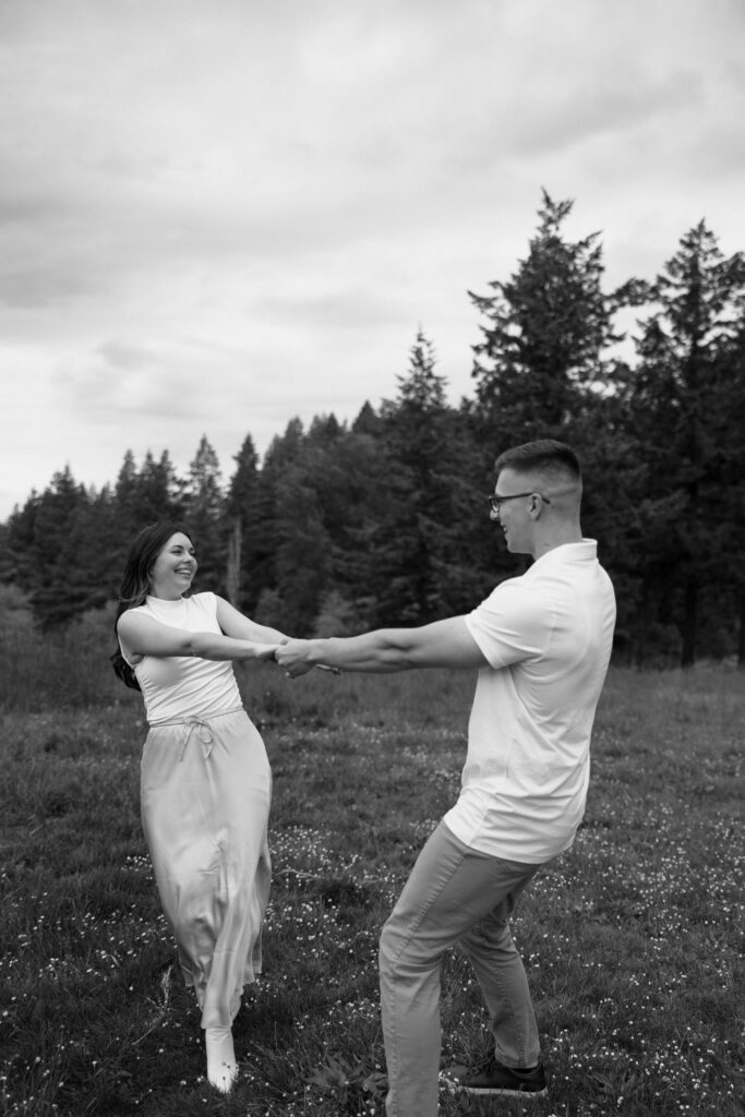 couple spinning around in open field at hoyt arboretum portland
