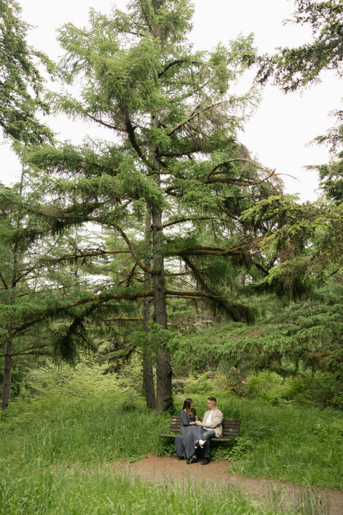 couple is sitting on bench at hoyt arboretum portland having a conversation