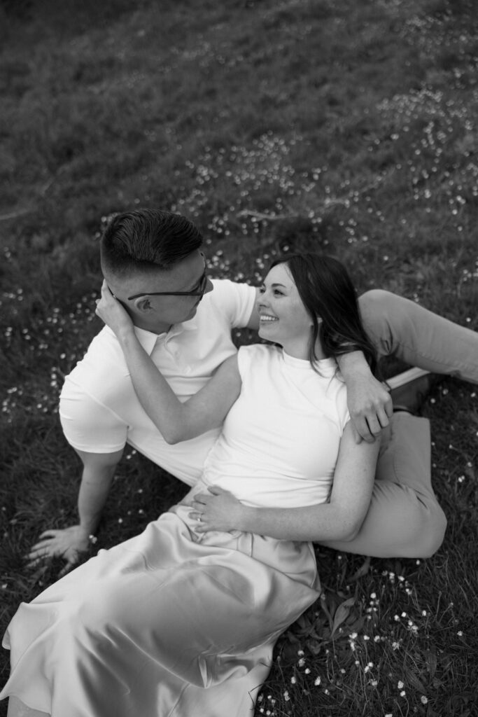 man sitting and woman laying on his lap smiling