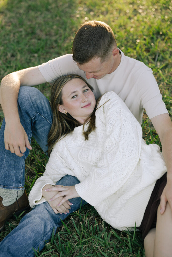 guy sitting down and girl laying on his lap looking at camera
