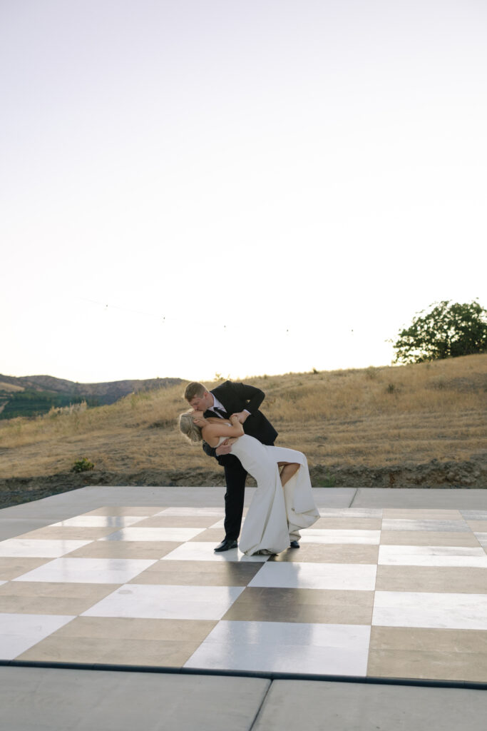 bride and groom dip on checked floor during first dance