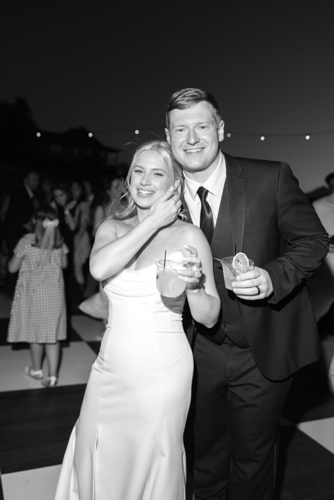 bride and groom smile for a photo with their drinks