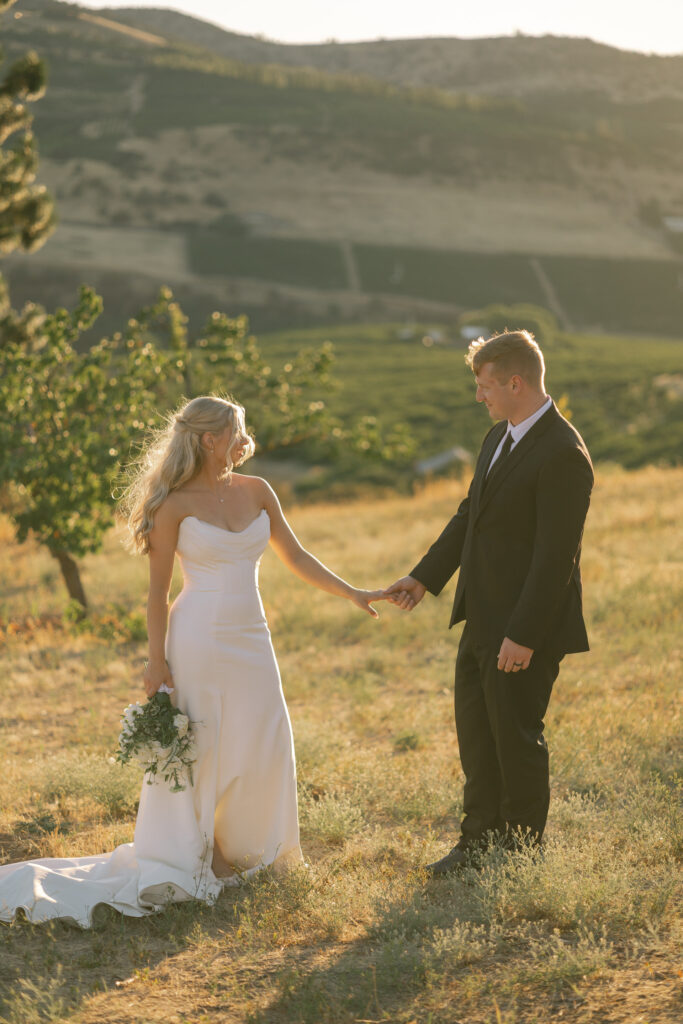 bride and groom standing in orchard looking at each other during sunset
