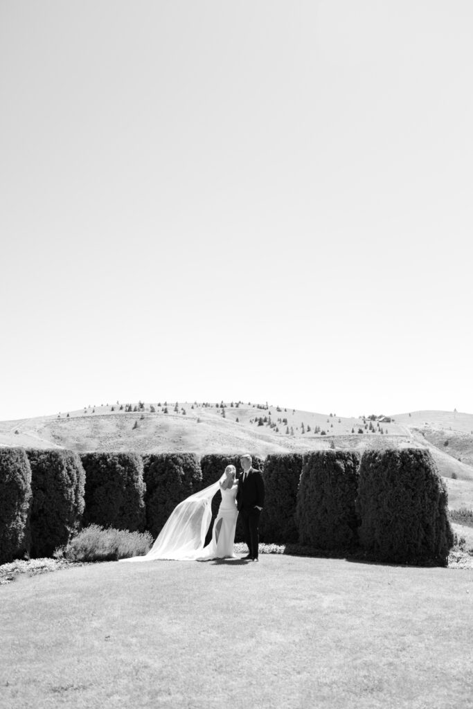 bride and groom standing in front of hedges in private garden in black & white
