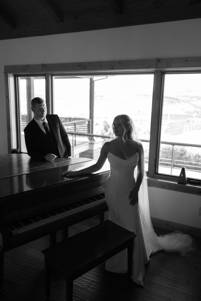 bride and grooms standing around piano in black & white