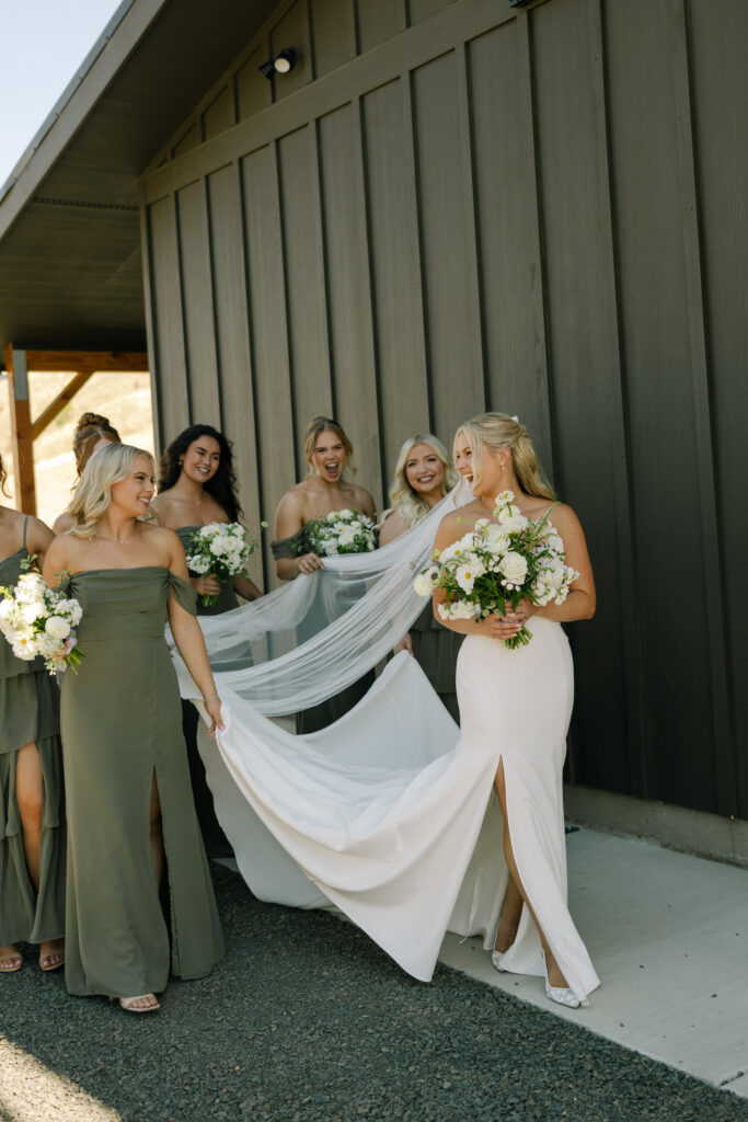 bridesmaids walking holding brides gown