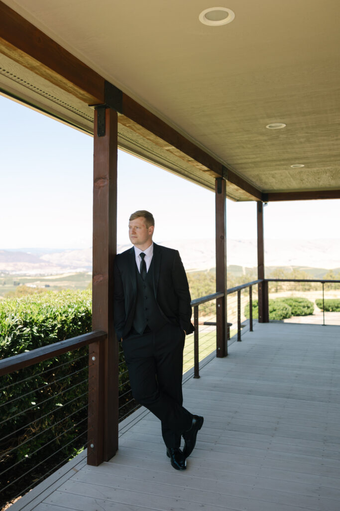 groom leaning against post looking into distance 