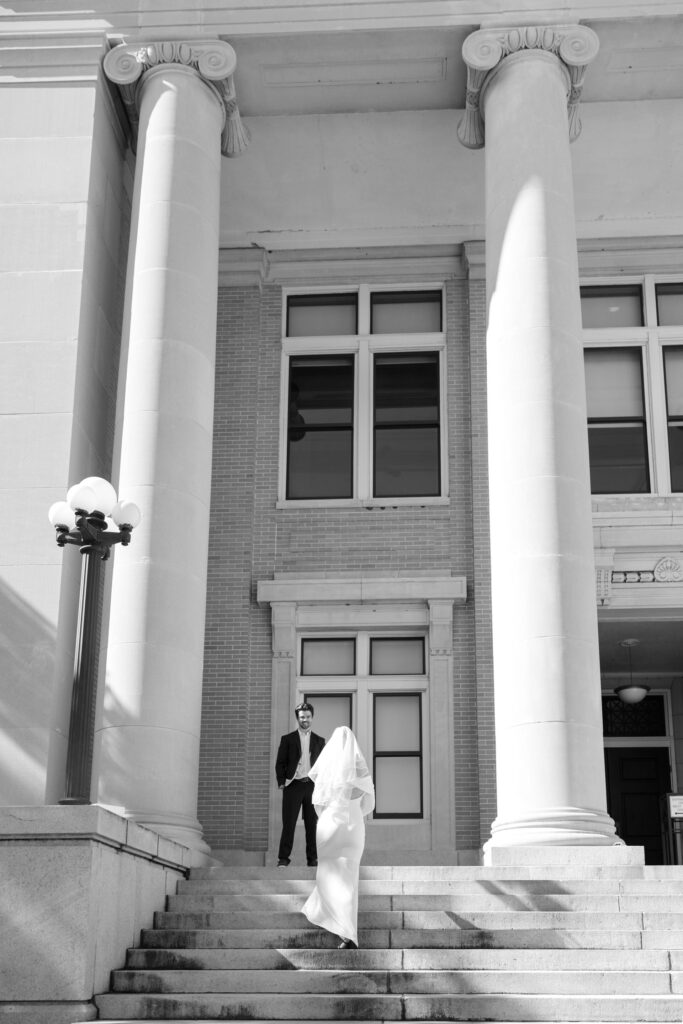 groom on platform of Old Pinellas County Courthouse and bride walking up to him